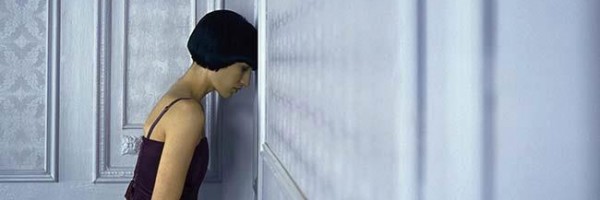 woman_standing_in_corner_leaning_head_against_wall_eyes_closed_IAI009000756